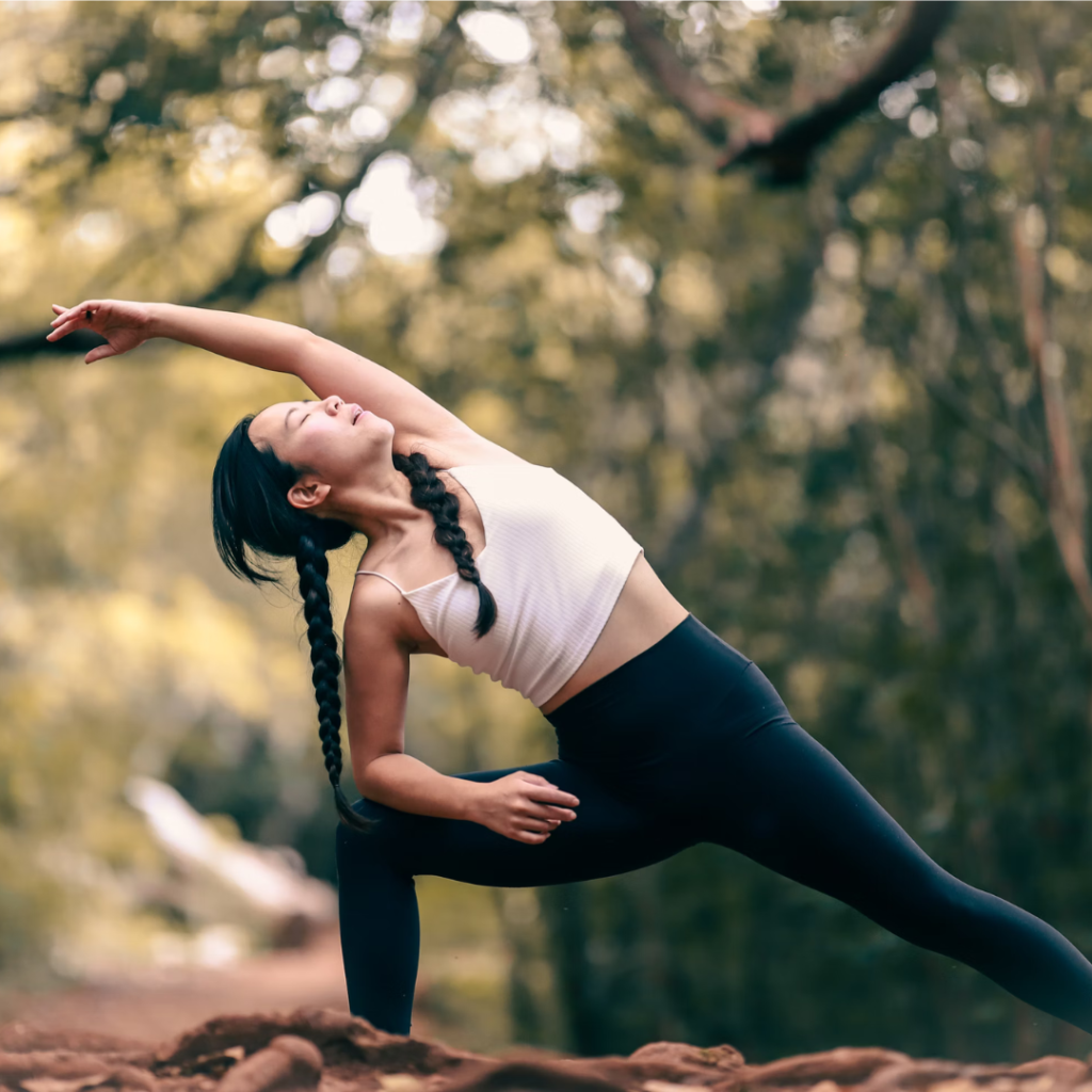 woman in white tank top and black leggings doing yoga during daytime