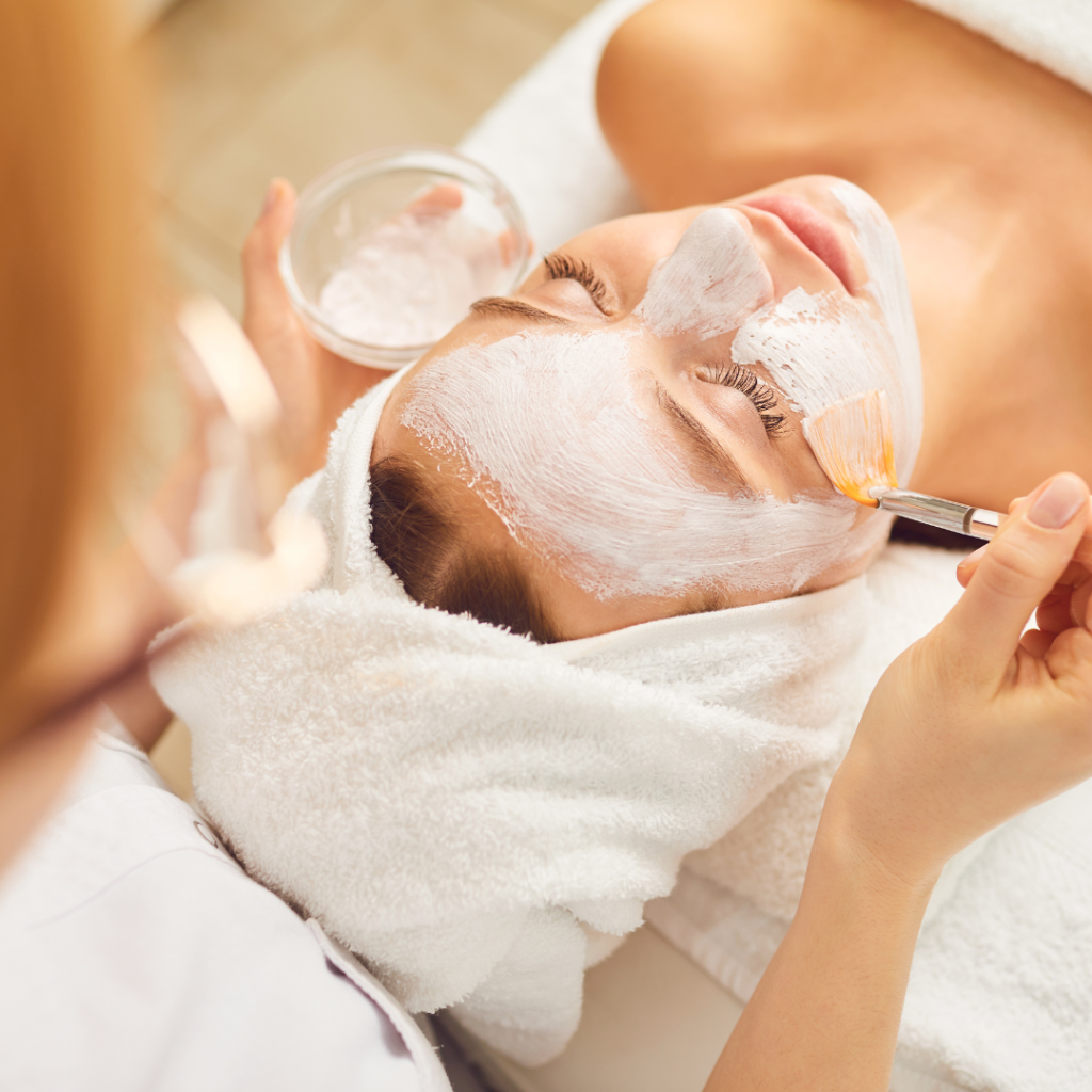 Young Girl Receiving White Facial Mask in Spa Beauty Salon.