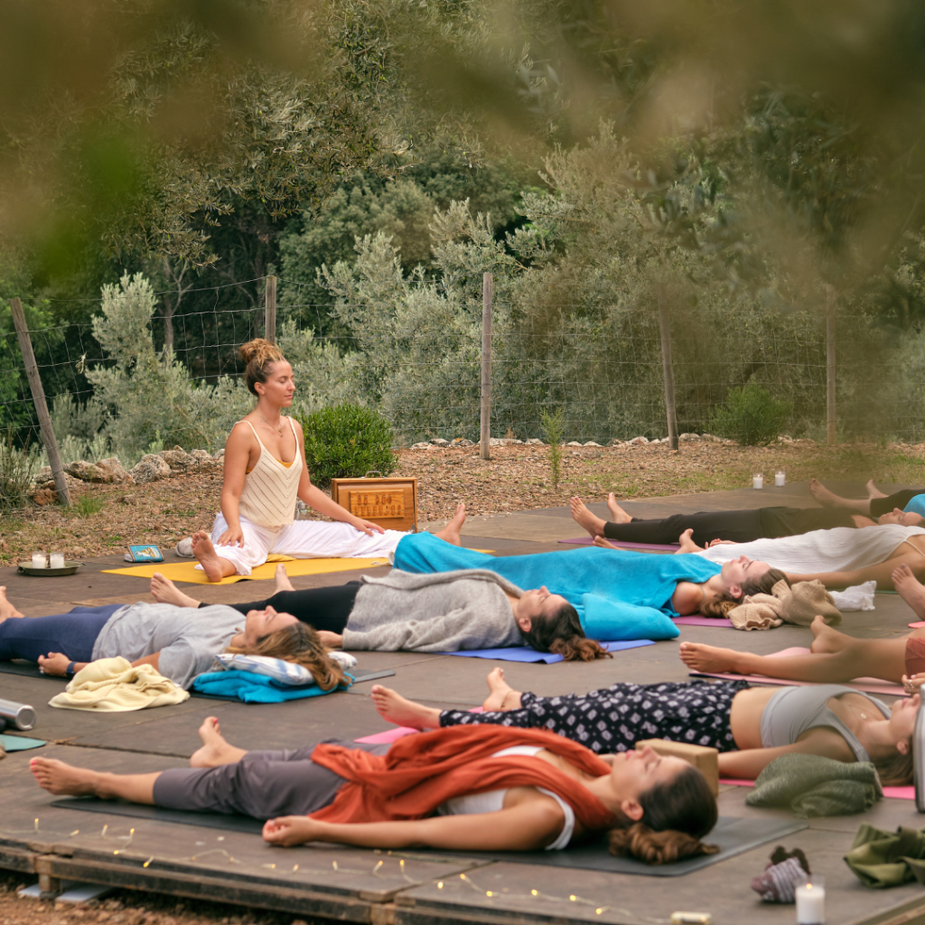 Women practicing yoga with instructor in nature