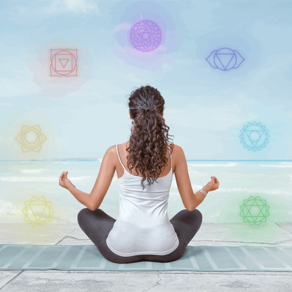Young woman is meditating on the beach with chakras glowing around her