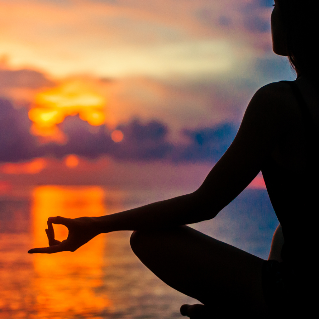 Woman meditating, relaxing in yoga pose at sunset, zen meditation