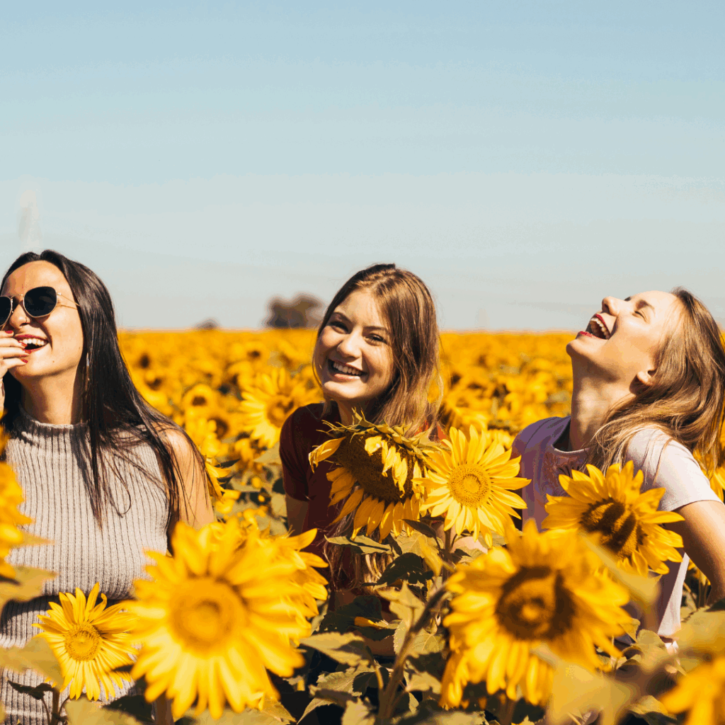 woman in white and black striped shirt standing on yellow sunflower field during daytime