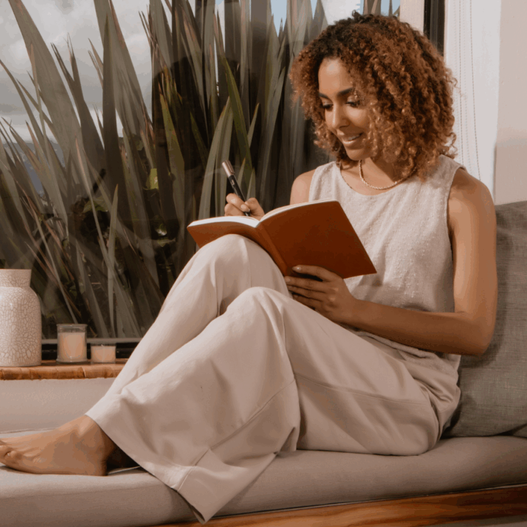 Woman Writing in Journal by Window at Home