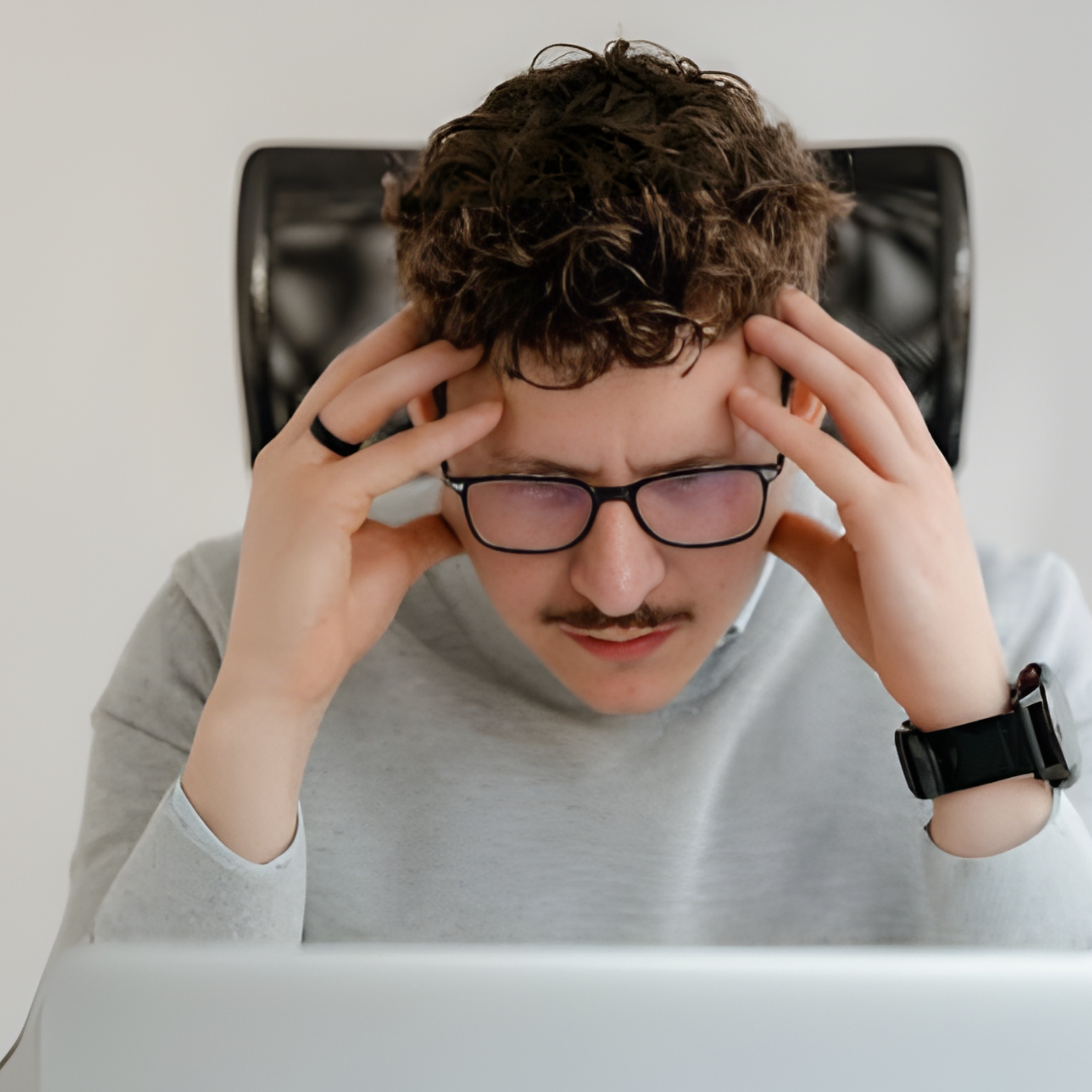 Person sitting at a desk with hands on temples, showing difficulty concentrating and mental strain